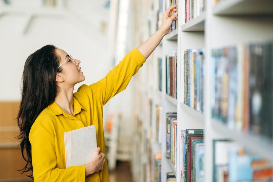 image of a person grabbing a book from the shelf