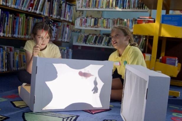 two girls sat in the library working on a project