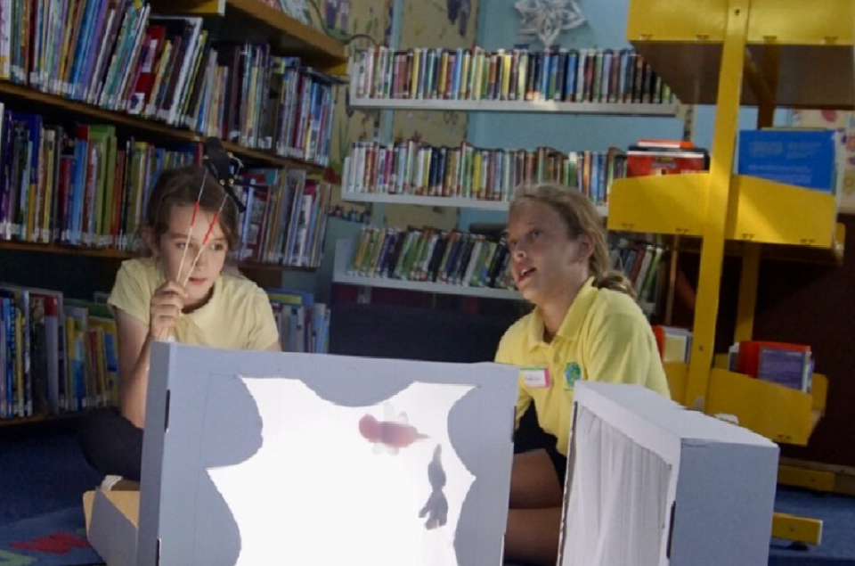two girls sat in the Children&#039;s library working on a project.