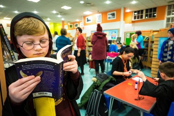 A boy dressed as Harry Potter reading a book