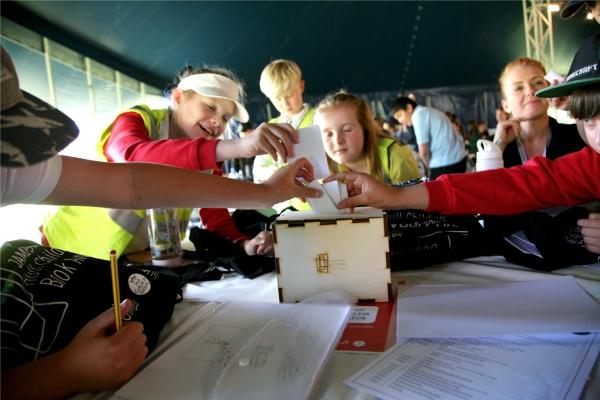 A group of children in hi-vis jackets putting paper in a box
